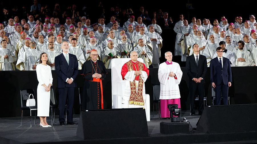 Ceremonia religiosa con la Reina Letizia, el Rey Felipe VI y el Papa León XIV, rodeados de clérigos en un ambiente solemne.