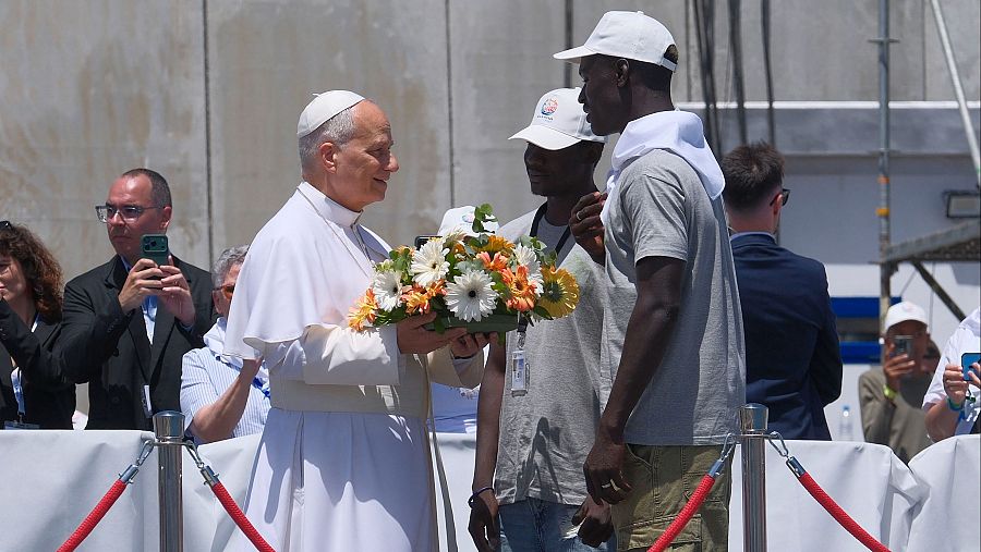 El papa León XIV recibe flores de dos voluntarios para protagonizar una ofrenda floral en el mar