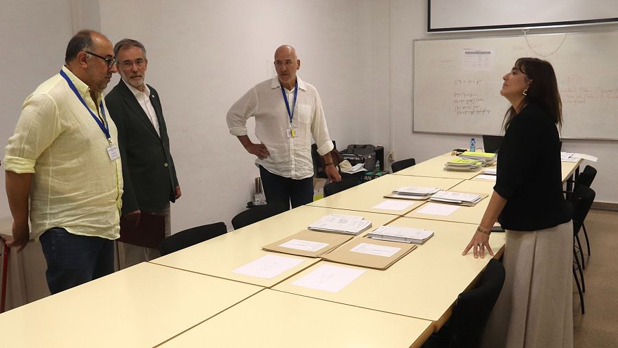 Natàlia Mas Guix, Consellera d'Economia i Hisenda, en una reunión con tres hombres en una sala moderna. Ella habla mientras ellos escuchan atentamente.