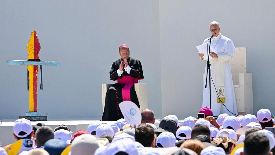 El Papa Francisco habla en un evento al aire libre en la Plaza del Cristo de la Laguna, acompañado por un obispo, ante una multitud con gorras blancas.