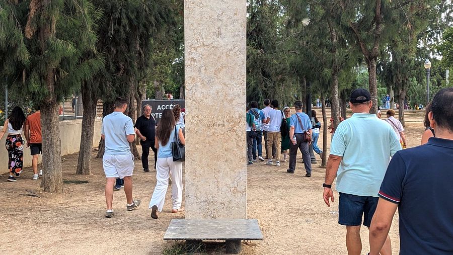 Fieles que se dirigen a la vigilia del papa en Montjuïc, Barcelona, pasan delante del monumento a Francesc Ferrer i Guàrdia