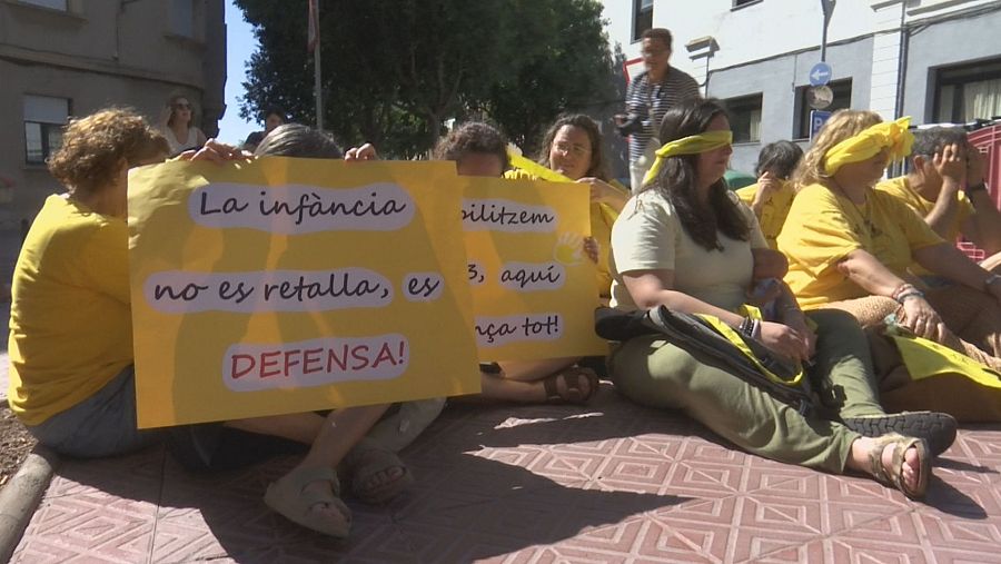 Manifestación en defensa de la infancia con personas vendadas y pancartas en catalán. 