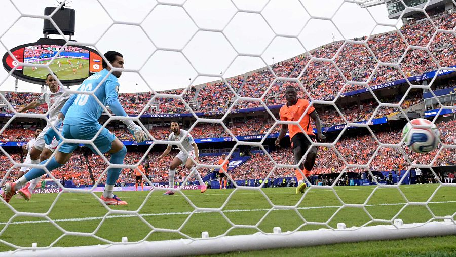 Brian Brobbey anota un gol para Países Bajos contra Túnez, visto a través de la red de la portería. El balón está en el aire, justo dentro de la red.