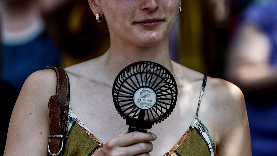 Una mujer usa un ventilador portátil para mitigar el calor en Berlín