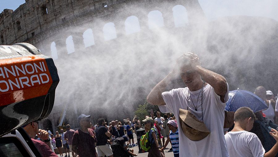 Los turistas se refrescan con nebulizadores de agua instalados cerca del Coliseo en Roma