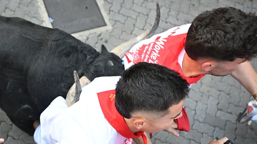 Dos mozos perseguidos cabeceados por uno de los toros durante el primer encierro