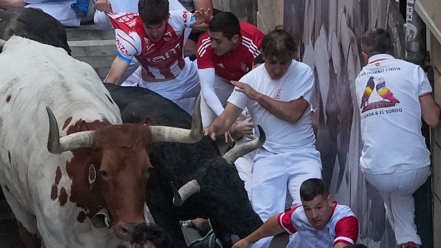 Varios mozos perseguidos por un cabestro y uno de los toros