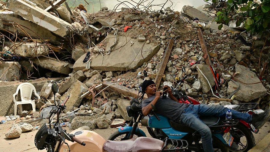Un hombre descansa sobre una motocicleta, entre los escombros de varios edificios derrumbados en Caraballeda, estado de La Guaira (Venezuela), el 10 de julio de 2026, tras los dos terremotos registrados el 24 de junio.