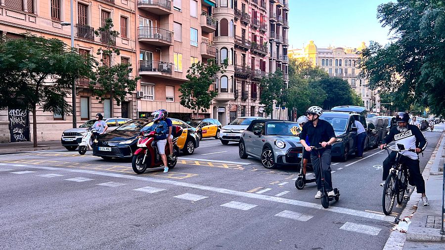 Diversos vehicles esperen a la calçada central i al carril bici del carrer Aragó de Barcelona abans que el semàfor es posi verd