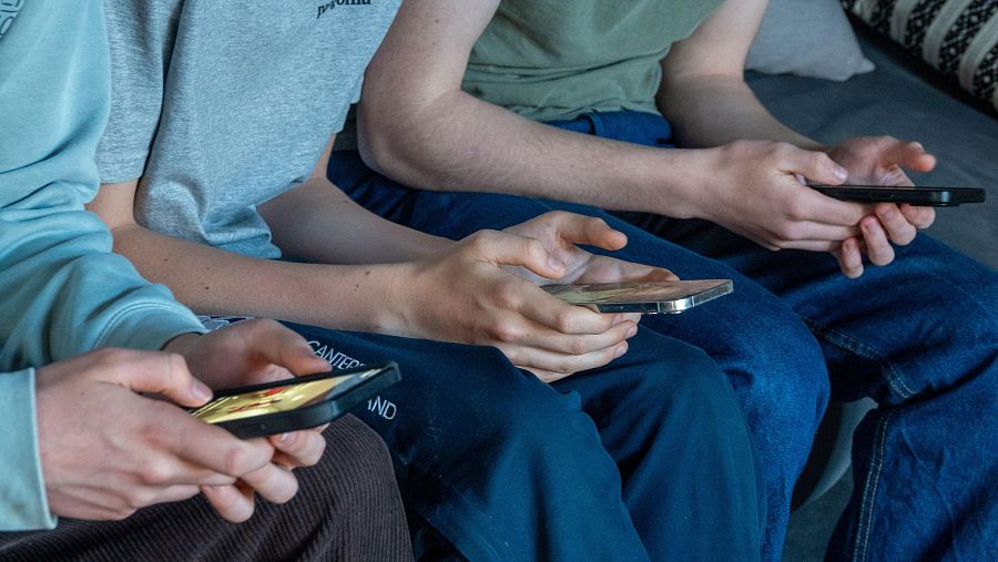 Tres adolescentes miran la pantalla de su teléfono móvil