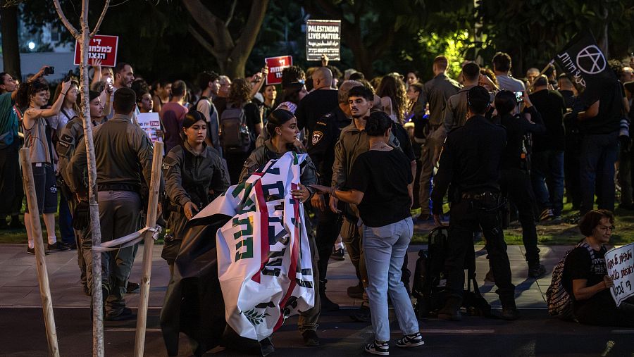 Manifestación nocturna en Israel con carteles en hebreo e inglés, incluyendo 