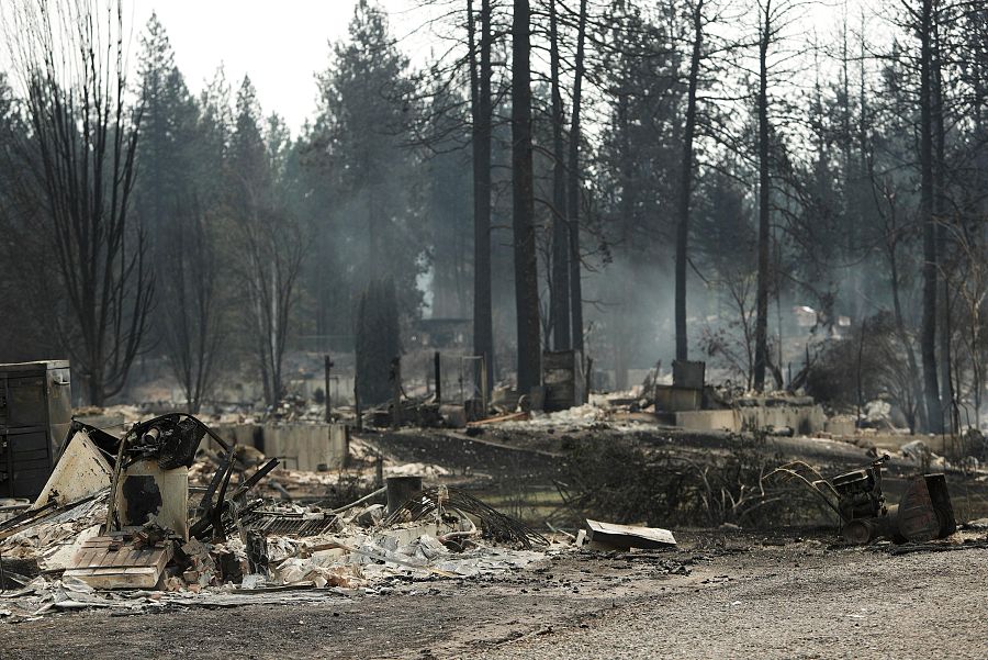 El humo se eleva desde las estructuras calcinadas tras un incendio forestal en una zona residencial de Westgate, cerca de la ciudad de Spokane, Washington