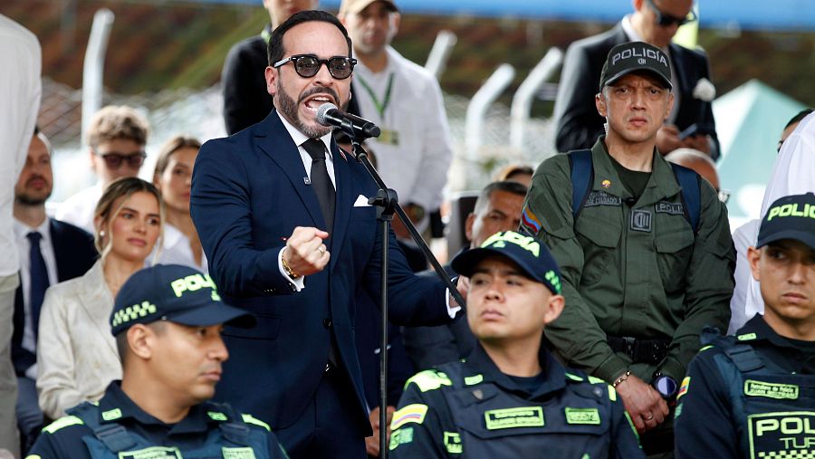 Abelardo de la Espriella da un discurso enérgico con el puño levantado, rodeado de policías en uniforme y civiles atentos. Se aprecian detalles como el micrófono, gafas de sol y un parche de la bandera colombiana.