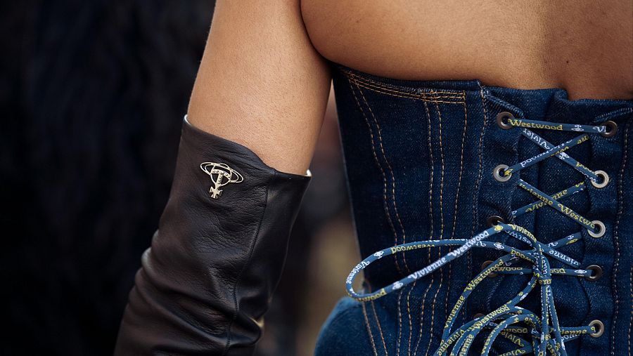 Una invitada a la Semana de la Moda de París combina un corsé de denim azul con una falda de tul negro y largos guantes de cuero frente al desfile de Vivienne Westwood, durante la jornada del 8 de marzo de 2025.