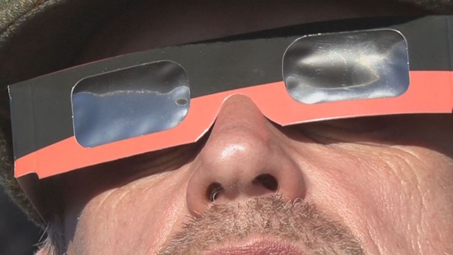 Hombre con gafas de eclipse, bigote y barba corta, mirando hacia arriba con concentración. Se aprecian filtros solares oscuros y marco de cartón.