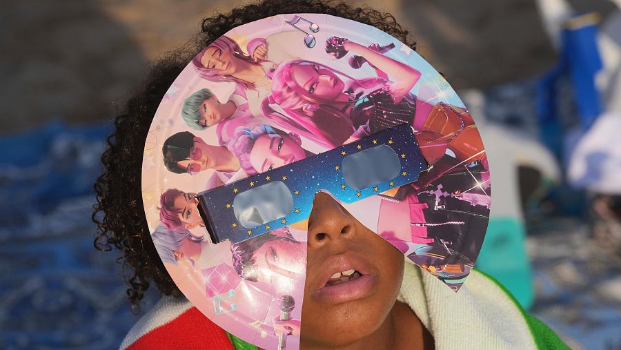 Una niña disfruta en la playa de Puerto de Sagunto en Valencia del eclipse con sus gafas personalizadas