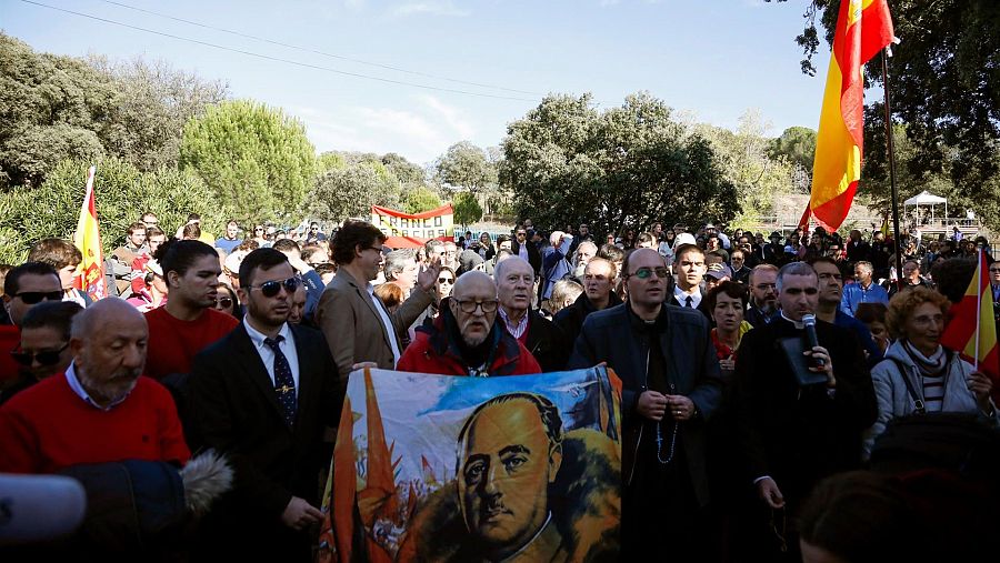 Manifestación al aire libre con pancartas de Franco, banderas de España y figuras políticas como Santiago Abascal y José Luis Roberto.