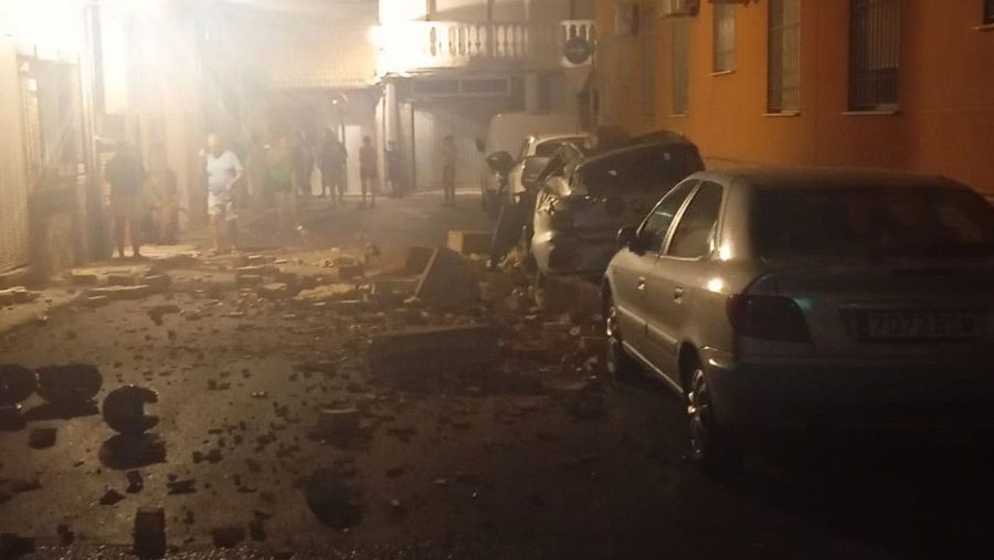 Calle de Granada con escombros y coches dañados tras un terremoto nocturno.