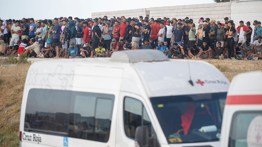 Miembros de la Cruz Roja atienden a varios inmigrantes, en la playa del Trampolín