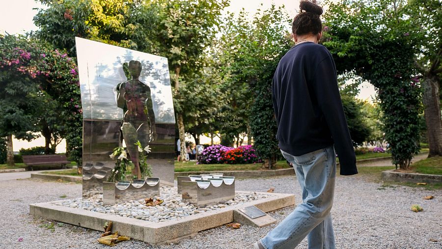 Una joven pasa frente a la estatua 'Como agua' en los jardines Valle Inclán de A Pobra de Caramiñal, que recuerda a las víctimas de violencia de género y a Diana Quer