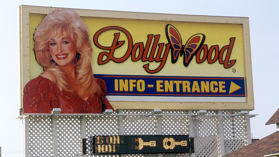 Cartel de entrada a DollyWood con Dolly Parton, fondo amarillo, borde dorado, 