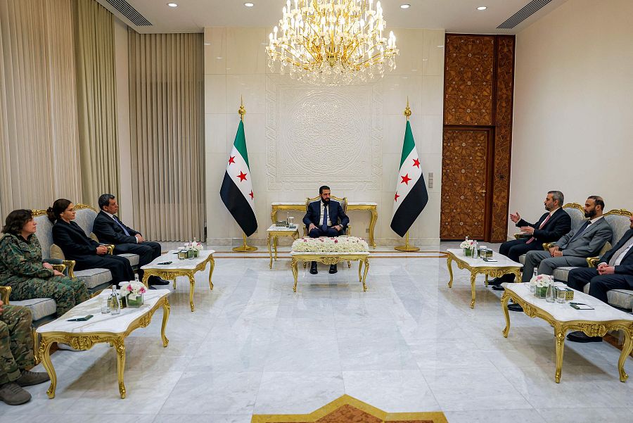 El presidente interino de Siria (C), su ministro de Asuntos Exteriores  (2.º por la derecha) y el líder kurdo (3.º por la izquierda), reunidos en el Palacio del Pueblo en Damasco
