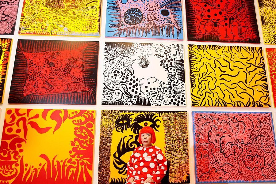 La artista japonesa Yayoi Kusama posa para los fotógrafos frente a su cuadro 'El amor llega a la Tierra llevando consigo un cuento del cosmos'