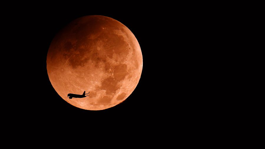 Un avión pasa por delante del eclipse lunar parcial sobre la ciudad costera israelí de Netanya