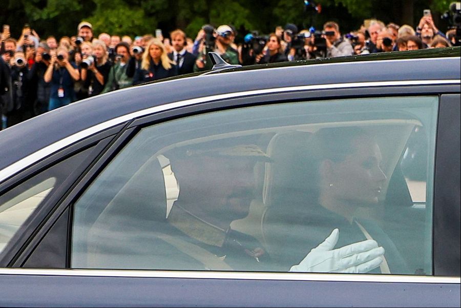 El rey Haakon y la princesa Ingrid Alexandra pasan en coche junto a las personas que acuden a rendir homenaje a los difuntos al llegar a una reunión extraordinaria del Consejo de Ministros en el Palacio Real