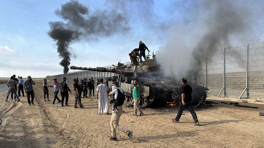 Miembros palestinos de las Brigadas Izz al-Din al-Qassam —el brazo armado de Hamás— incendian un vehículo militar blindado de las fuerzas israelíes cerca de la Franja de Gaza, en Gaza, el 7 de octubre de 2023