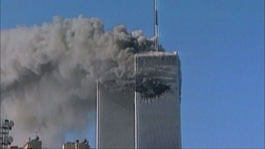 Torre Norte del World Trade Center en llamas y emitiendo humo negro denso hacia un cielo azul, tras el impacto de un avión.
