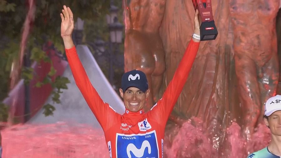 Enric Mas, ciclista de Movistar, celebra con un trofeo rojo y negro, posiblemente de 