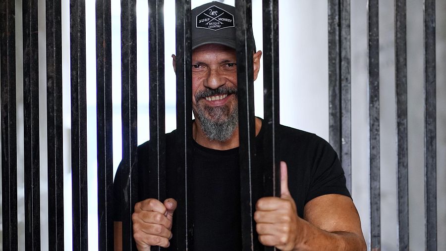 César Pérez Gellida, escritor español, sonríe a la cámara sujetando barras metálicas. Lleva camiseta negra y gorra 