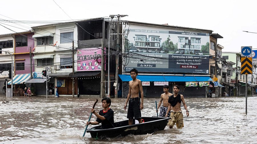 Un grupo de jóvenes utiliza una barca para desplazarse por las calles inundadas