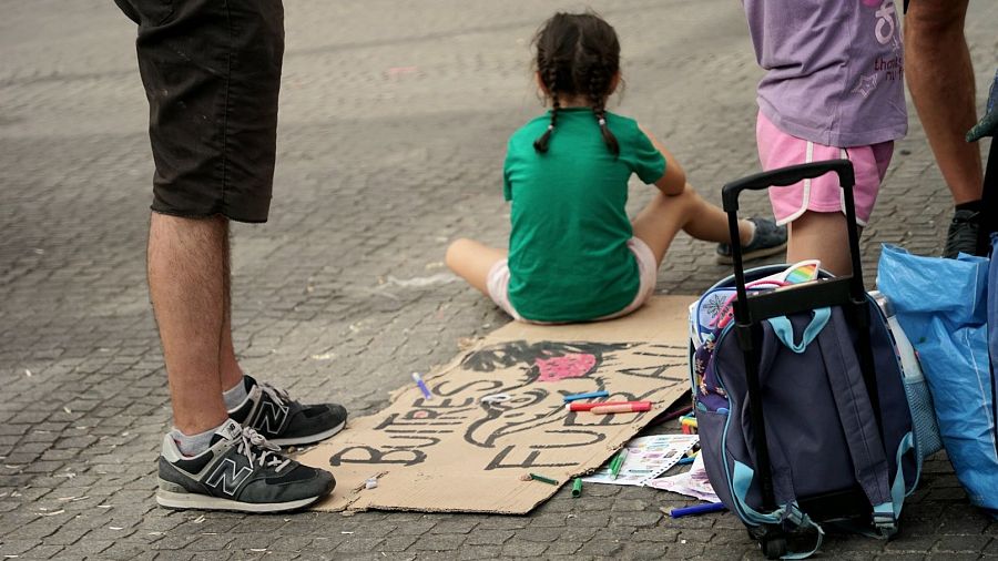 Una niña junto a un cartel de 'Buitres fuera' en la acampada de Sol