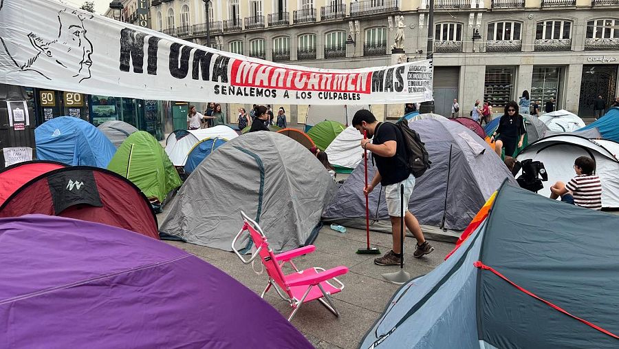 Un joven limpia alrededor de su tienda de campaña, en la Puerta del Sol de Madrid.