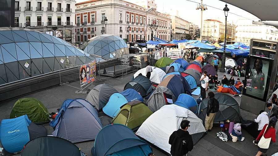 Campamento de manifestantes con tiendas de campaña de colores en la Puerta del Sol de Madrid, junto al acceso del metro y frente a la Real Casa de Correos.
