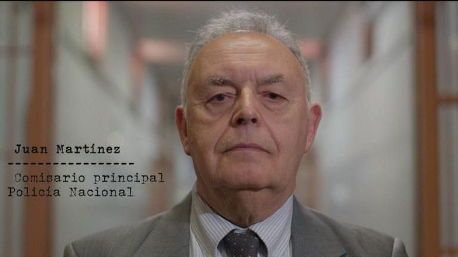 Plano medio de Juan Martínez, comisario principal de la Policía Nacional, con traje gris y corbata, junto a un texto con su nombre y cargo.