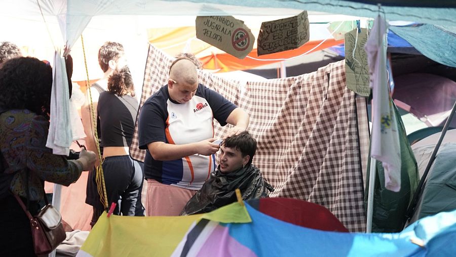 Un joven corta el pelo a otro en la acampada de Sol, este martes