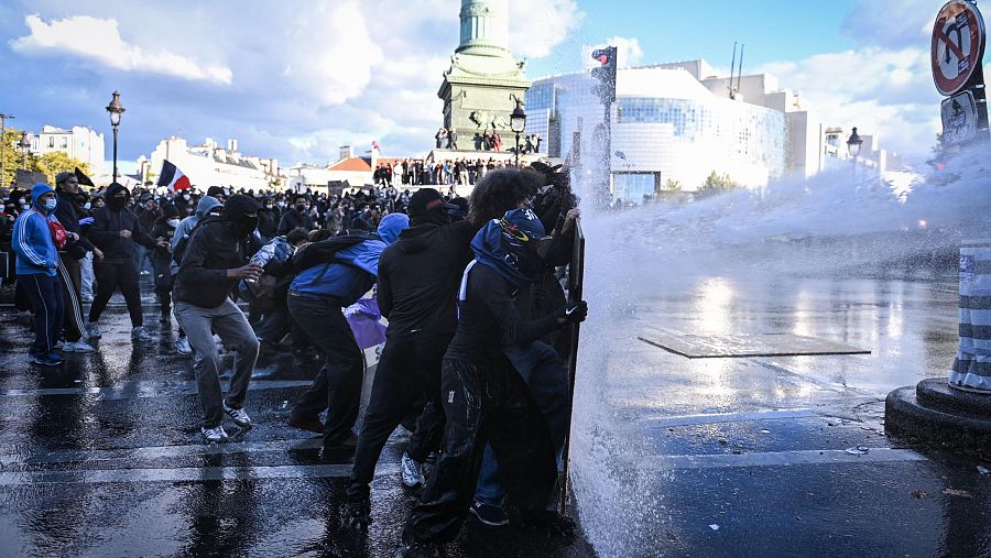 Manifestantes resisten el cañón de agua de la policía antidisturbios mientras se producen enfrentamientos en la plaza de la Bastilla.