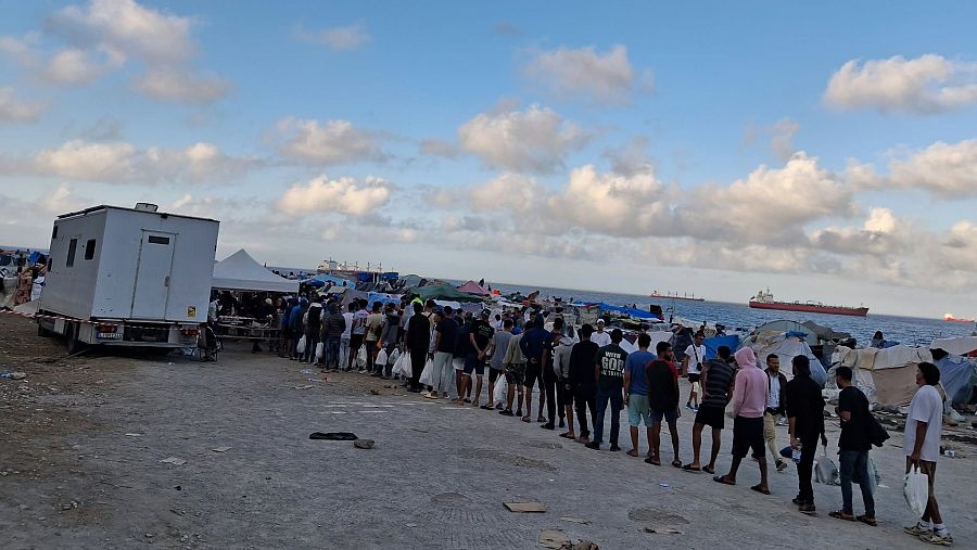 Filas de inmigrantes esperan para recibir productos básicos para sobrevivir en la playa de El Guano.
