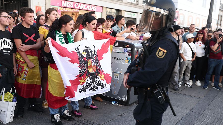 Un grupo de personas se desplaza del desfile por la Fiesta Nacional a la acampada de Sol, generando momentos de tensión