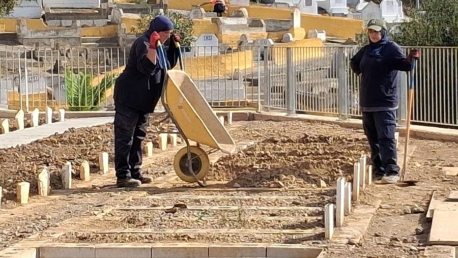 Dos operarias ultiman detalles antes de la visita real al cementerio musulmán.