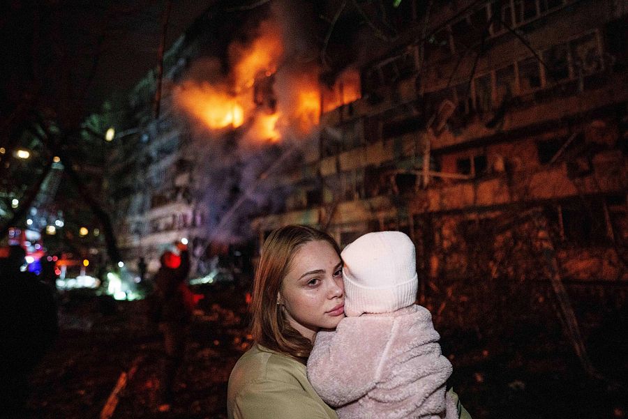 Una mujer sostiene a su hija frente a un edificio residencial dañado por un ataque con misiles rusos en Kiev