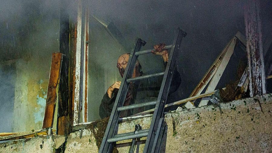 Leonid, un residente local herido, espera a los rescatistas en su balcón en un edificio residencial dañado por un ataque con misiles rusos en Kiev