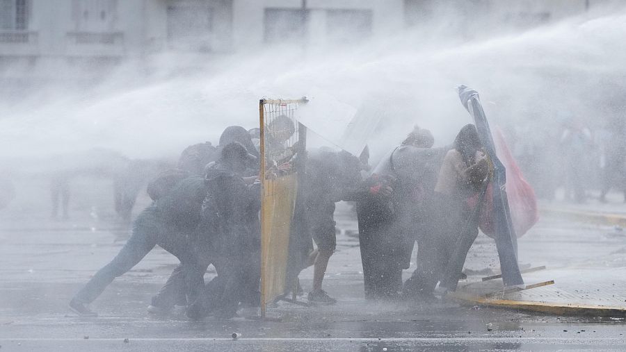 Los manifestantes se protegen de los cañones de agua