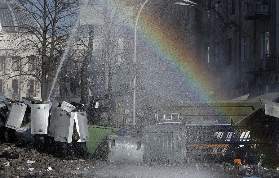 Un arcoiris aparece sobre varios policías antidisturbios durante los choques entre opositores y policía