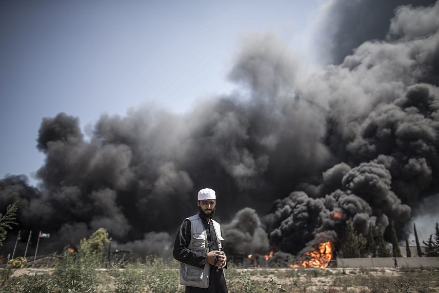 Un hombre palestino camina cerca del fuego originado en la central eléctrica principal de Gaza después de los bombardeos nocturnos de los israelíes. EFE/Oliver Weiken