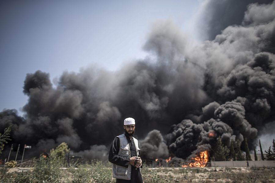 Un hombre palestino camina cerca del fuego originado en la central eléctrica principal de Gaza después de los bombardeos nocturnos de los israelíes. EFE/Oliver Weiken