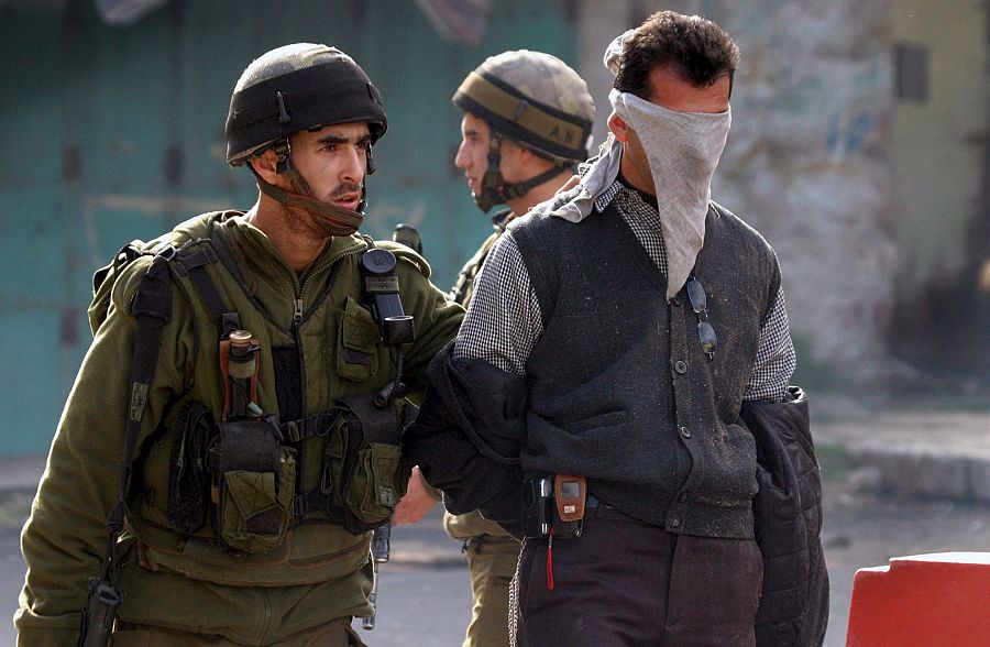 Un soldado israelí arresta a un palestino en una operación militar israelí en la ciudad cisjordana de Hebrón. 22/01/2006